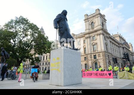 Un manifestant de la rébellion d'extinction défait la statue de Winston Churchill sur la place du Parlement au cours du dernier jour de la manifestation des groupes à Londres. Banque D'Images