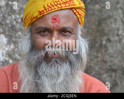 Le vieux mendiant népalais et le dévot hindou avec la marque de riz rouge tilak sur son front sourit pour la caméra. Banque D'Images