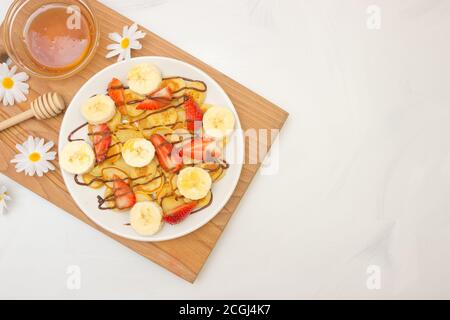 Plats tendance - céréales à crêpes. Tas de mini crêpes aux céréales sur une assiette blanche, espace de copie. Fraises, bananes et miel. Un Bre beau et sain Banque D'Images