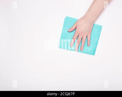 Partie de la main avec un chiffon bleu pour épousseter et enlever la saleté. Nettoyage, arrière-plan blanc, espace libre pour le texte. Banque D'Images