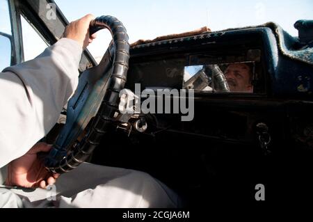 Un chauffeur de taxi égyptien tenant le volant, son visage se reflète sur un miroir de tableau de bord, dans sa cabine au Caire, en Égypte. Banque D'Images