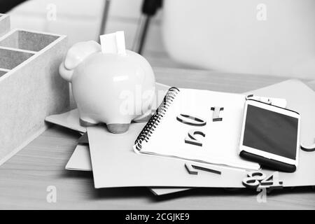 Des papiers différents avec des nombres, cahier, rose cochon Piggy Bank et du téléphone cellulaire sur la table en bois brun Banque D'Images