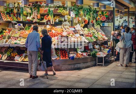 Les personnes portant un masque et achetant dans un stand de fruits et légumes dans le marché intérieur, Mercado de la Encarnación Banque D'Images