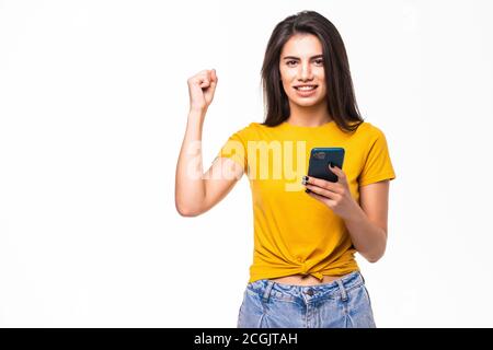 Portrait d'une femme heureuse tenant un téléphone portable et célébrant une victoire isolée sur fond blanc Banque D'Images