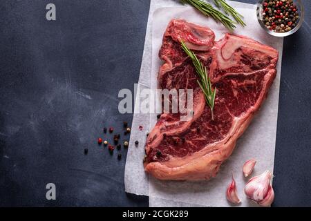 Steak d'os frais brut sur fond sombre, vue du dessus. Banque D'Images