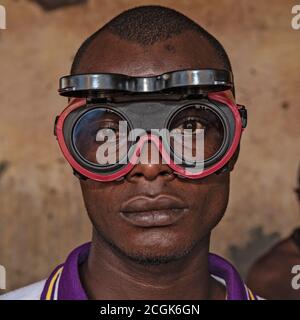 Portrait d'un adolescent africain jeune, portant des lunettes de protection, avec arrière-plan à l'extérieur Banque D'Images