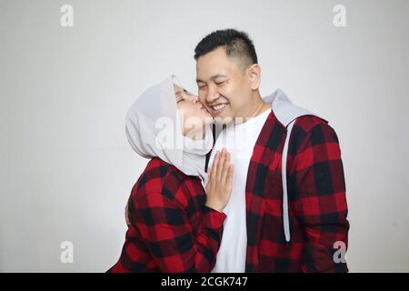 Portait de heureux couple asiatique musulman souriant, mari et femme embrassant et embrassant plein d'amour, concept de famille Banque D'Images