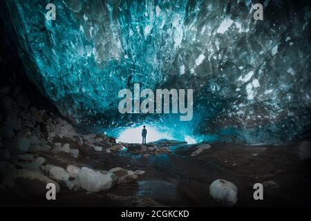 Grotte de glace de femme dans un glacier de montagne, une colonne de glace la plus pure est suspendue au-dessus des pierres de la grotte d'Alibek, glacier de Dombay, Russie Banque D'Images