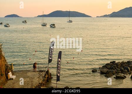 Vue sur le golfe de la Spezia avec un couple embrassé sur la rive et l'archipel de Porto Venere avec les îles Tino et Palmaria au coucher du soleil, Italie Banque D'Images