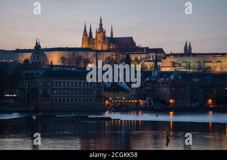 La nuit commence à tomber sur la ville et les lumières de la ville se reflètent sur la rivière Moldava, Prague, République tchèque Banque D'Images