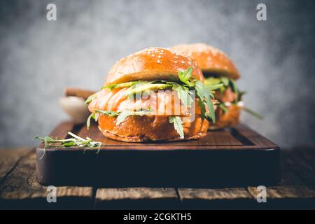 Hamburger sandwich avec saumon, fromage à la crème, avocat et arugula sur un fond clair, concept de nourriture de régime, sandwich à emporter, nourriture saine et rapide Banque D'Images