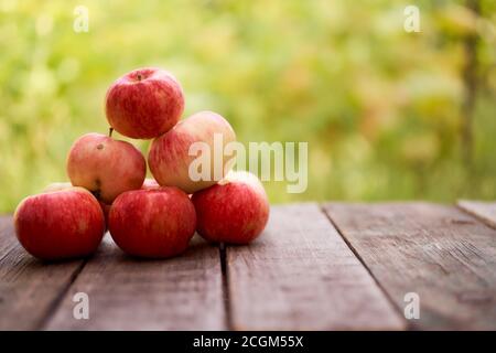 Les pommes rouges sont sur une planche en bois. Arrière-plan vert flou. Gros plan. Banque D'Images