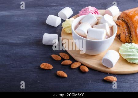 une tasse de chocolat chaud avec guimauve, pain et meringues sur fond noir en bois. gros plan, espace de copie. Banque D'Images