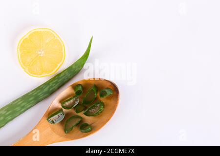 Aloe vera feuilles fraîches avec des tranches et du gel sur une cuillère en bois. Isolé sur blanc. L'aloe vera est une herbe médicinale populaire utilisée pour la santé et la beauté. Banque D'Images