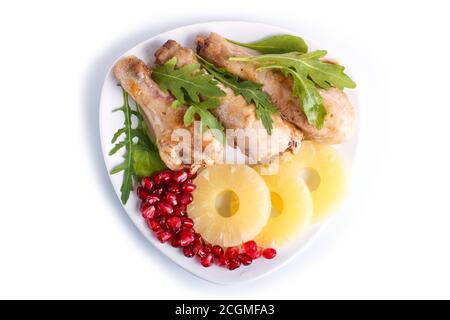 Cuisses de poulet frites avec rucola, ananas et graines de grenade isolées sur fond blanc, vue du dessus. Banque D'Images
