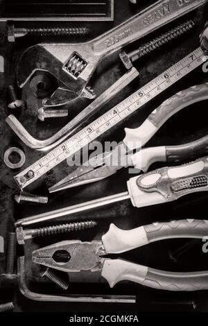 Anciens outils et vis sur un fond métallique photographiés à l' noir et blanc Banque D'Images
