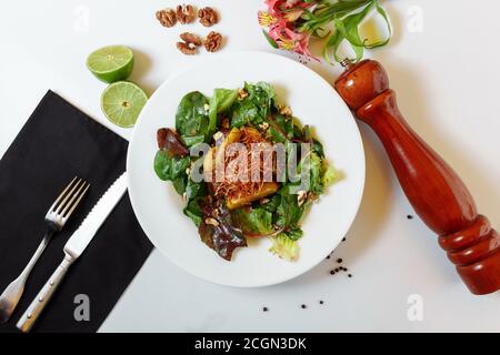 Salade avec foie caramélisé et couscous. Mélange à salade, foie de poulet caramélisé aux pommes, couscous, sauce framboise, tarte aux pommes de terre, noix Banque D'Images