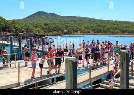 Rangitoto Island, Nouvelle-Zélande. Une foule de touristes attendent un ferry au quai. En arrière-plan se trouve le cône volcanique de l'île Banque D'Images