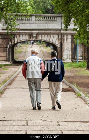 Un couple de personnes âgées bien habillé et vivant montre leur amour en tenant les mains pendant qu'elles se promènent dans un parc dans le centre de Paris un bel après-midi. Banque D'Images