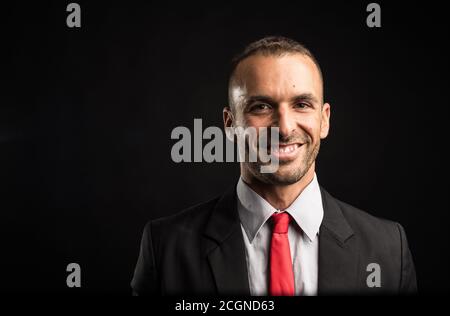 Homme beau et souriant en costume. Gros plan. Arrière-plan noir. Banque D'Images