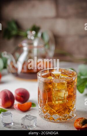 Verre de thé glacé à la pêche ou à l'abricot avec tranches de fruits sur fond blanc Banque D'Images