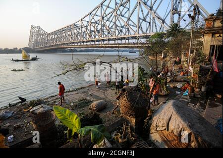 22.02.2011, Kolkata (Calcutta), Bengale-Occidental, Inde, Asie - gens à Mallick Ghat le long de la rive de la rivière Hooghly avec le pont Howrah. Banque D'Images