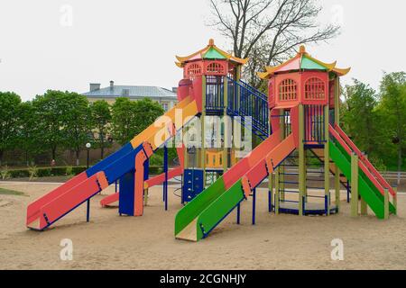 Terrain de jeu coloré pour enfants sur une cour de sable à proximité de beaux bâtiments. Banque D'Images