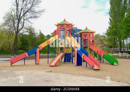 Terrain de jeu coloré pour enfants sur une cour de sable à proximité de beaux bâtiments. Banque D'Images