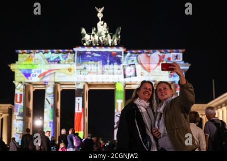 Berlin, Allemagne. 11 septembre 2020. Les visiteurs prennent des selfies devant la porte de Brandebourg illuminée lors du Festival des lumières de Berlin, capitale de l'Allemagne, 2020 septembre 11, 2020. Berlin, vendredi, s'est transformée en ville d'art léger avec l'ouverture du Festival des lumières de 2020 qui durera jusqu'au 20 septembre. Credit: Shan Yuqi/Xinhua/Alay Live News Banque D'Images