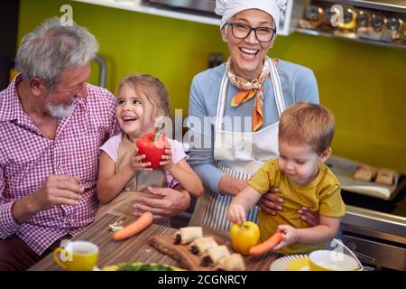 vue de dessus des grands-parents appréciant avec leurs petits-enfants dans la cuisine, riant Banque D'Images