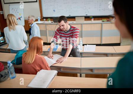 Étudiant aidant un collègue dans une pause d'une conférence à amphithéâtre Banque D'Images