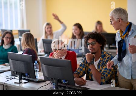 Professeur féminin répondant à la question de l'étudiant lors d'une conférence informatique dans la salle de classe informatique de l'université Banque D'Images