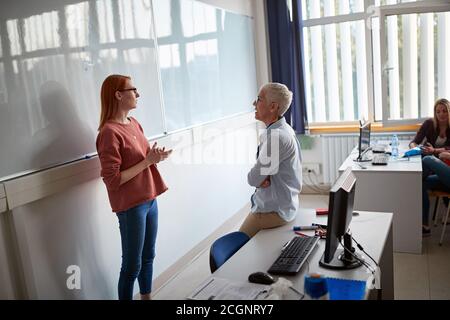 Professeur de sexe féminin questionnant un étudiant lors d'une conférence informatique à la salle de classe informatique universtiy Banque D'Images