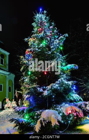 Sapin de Noël illuminé dans un village pittoresque. Soirée à côté de l'arbre de Noël dans le village en tchèque. Banque D'Images