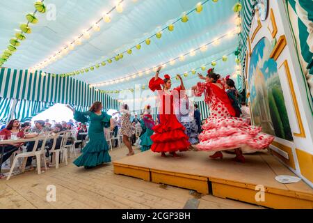 Jeune femme dansant Sevillano, femme espagnole avec des robes de flamenco dans le chapiteau coloré, Casetas, Feria de Abril, Séville, Andalousie, Espagne Banque D'Images