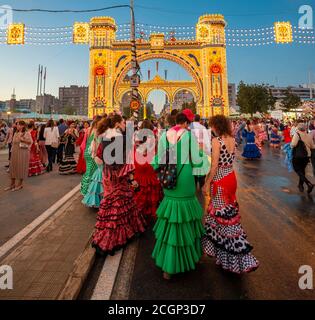 Femmes espagnoles avec des robes de flamenco devant la Portada illuminée, porte d'entrée, Feria de Abril, Séville, Andalousie, Espagne Banque D'Images