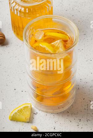 mise au point sélective, un grand verre de thé glacé au citron avec un pot de miel sur un fond clair Banque D'Images