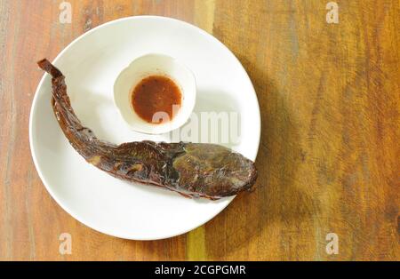 poisson-chat grillé en trempant avec une tasse de sauce épicée sur l'assiette Banque D'Images