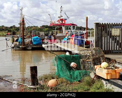 Bateau de pêche en activité amarré à un ponton sur la rivière Blyth dans le port de Southwold, Suffolk avec des filets et des pots entreposés prêts à l'emploi. Banque D'Images