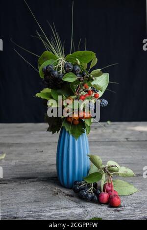 Vase bleu avec une composition de baies sauvages sur un tableau Banque D'Images