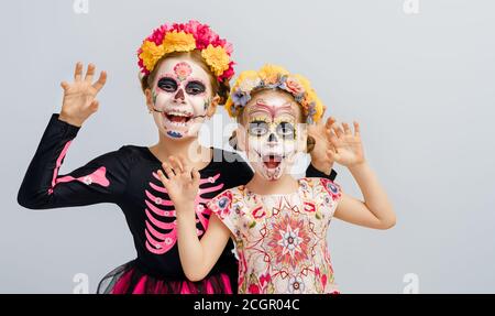 Des zombies adorables dans des couronnes de fleurs posant sur fond blanc. Des enfants heureux avec le maquillage créatif d'Halloween. Les filles célèbrent pour la fête mexicaine du Banque D'Images