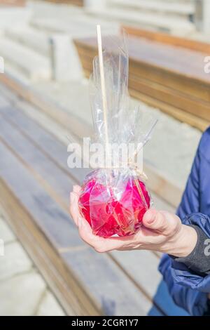 pomme au caramel rouge à la main féminine, dessert sucré de la foire de la ville Banque D'Images