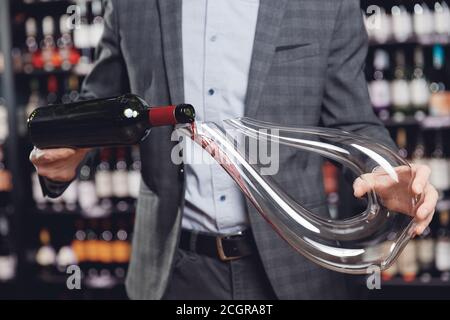 L'homme sommelier verse le vin rouge dans un décanteur pour l'aération du goût et de l'arôme Banque D'Images