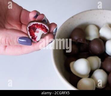 la main de femme choisit et attrapant rouge frais et brillant frais framboises enrobées de chocolat noir et blanc fait maison Banque D'Images