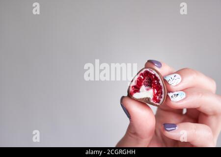 la main de femme choisit et attrapant rouge frais et brillant frais framboises enrobées de chocolat noir et blanc fait maison Banque D'Images