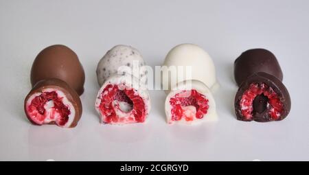 framboises trempées ou recouvertes de chocolat en moule coupé en deux. Différentes saveurs : chocolat blanc, chocolat au lait, chocolat noir et biscuits Banque D'Images