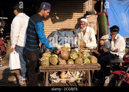 Un vendeur mobile dans la région de Bhendi Bazar, Mumbai, Inde, vendant des noix de coco de son poussette Banque D'Images