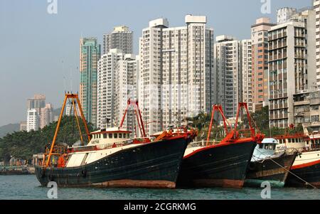 Aberdeen, Hong Kong, Chine. Bateaux de pêche amarrés dans le port d'Aberdeen sur l'île de Hong Kong. Les grands bâtiments d'Aberdeen sont derrière. Banque D'Images