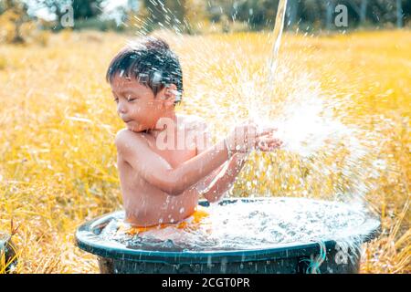 Les garçons jouaient avec de l'eau dans les champs heureusement. Banque D'Images