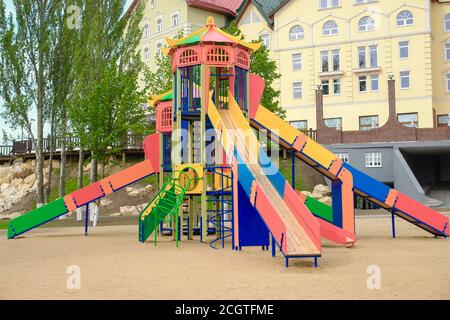 Terrain de jeu coloré pour enfants sur une cour de sable à proximité de beaux bâtiments. Banque D'Images